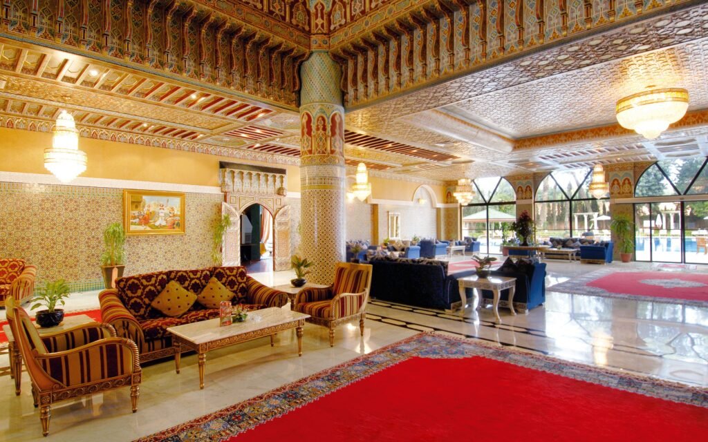 Sophisticated Moroccan hotel lobby with ornate decor, plush seating, and chandeliers.
